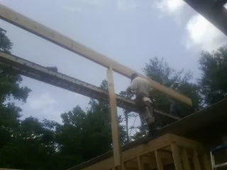 Carpenter setting a ridge beam over a new addition frame — Ice Dam Removal by Roofing Brothers in New Athens