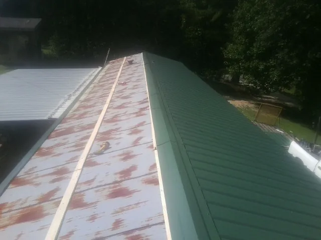 Old rusted panels beside newly installed green metal roofing — Wind Damage Roof Repair by Roofing Brothers in New Athens