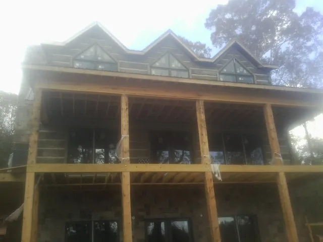 Dormers and porch framing on a large log home under construction — Roof Coating work by our crew in New Athens