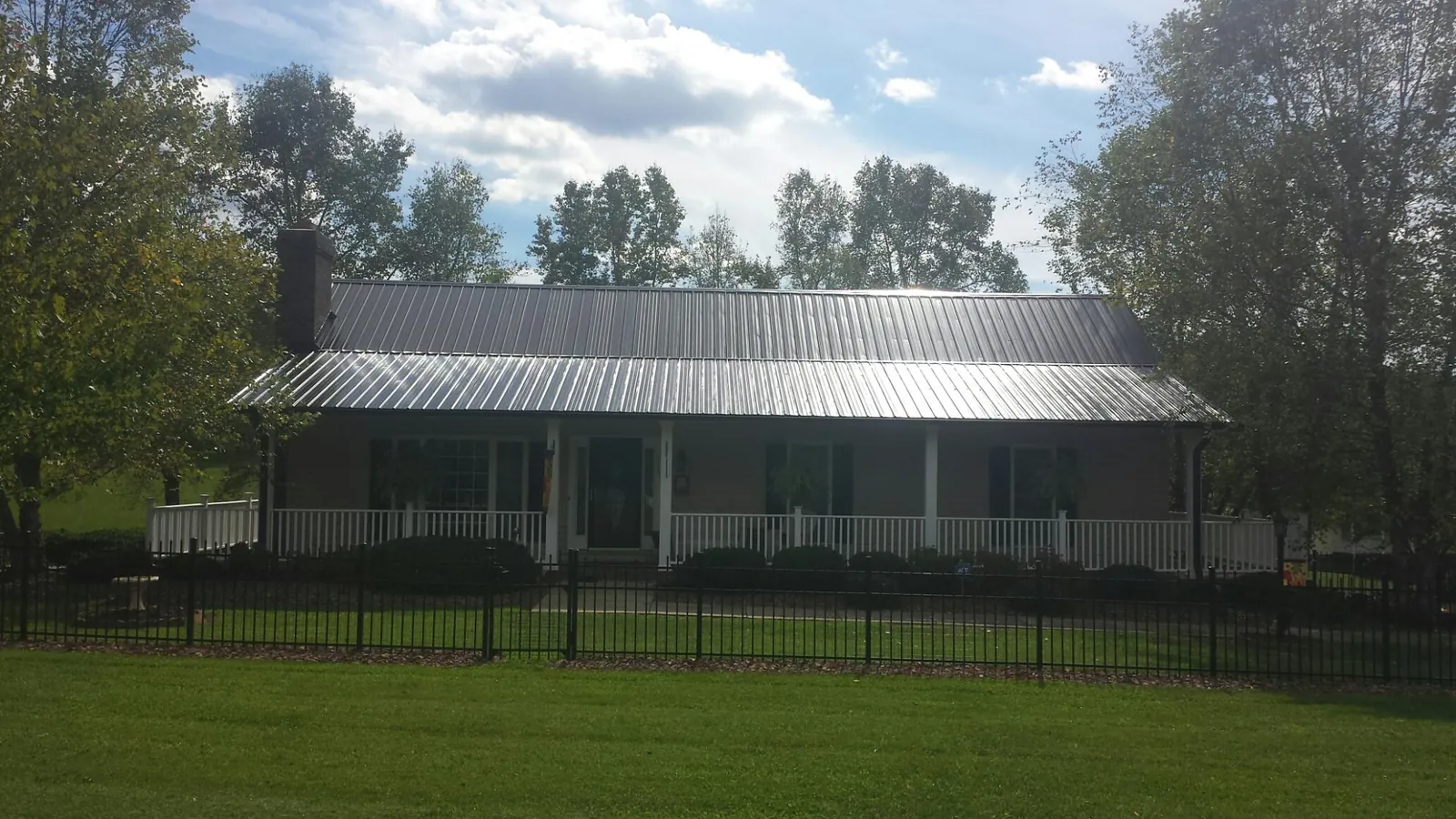 Gray metal roof on a brick ranch with a full width front porch — Gutter Guard Installation work by our crew in New Athens