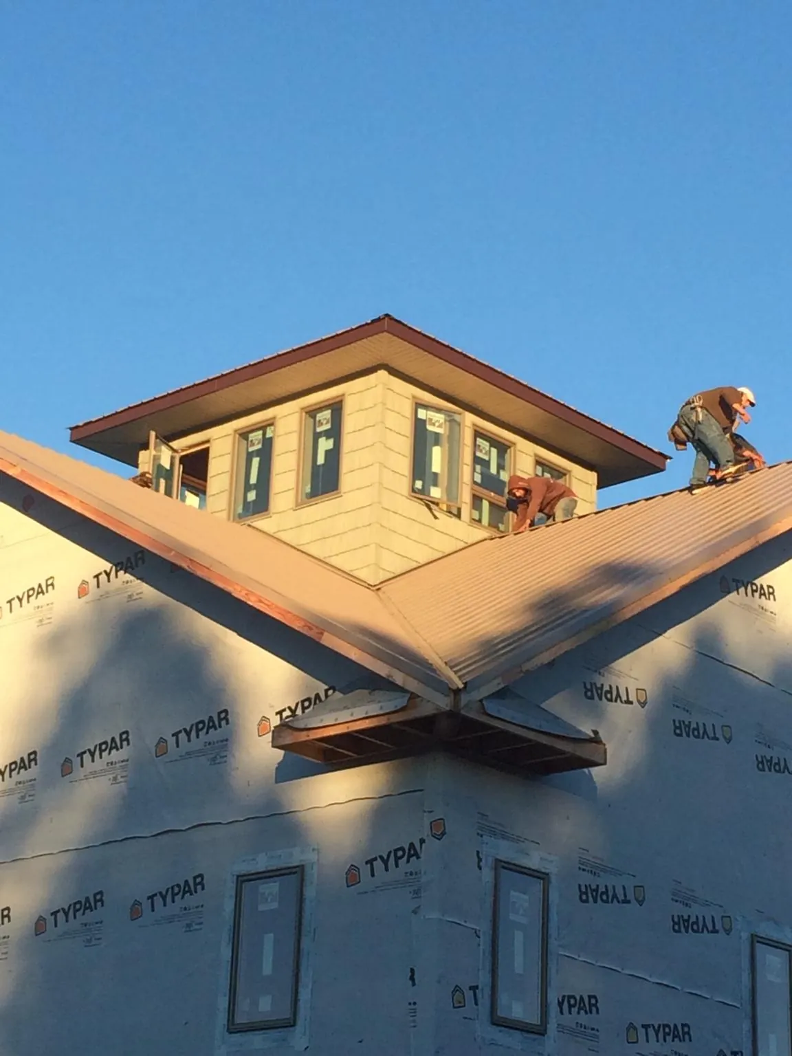 Roofers working around a rooftop cupola on a new metal roof at sunset — Roof Waterproofing in New Athens by Roofing Brothers